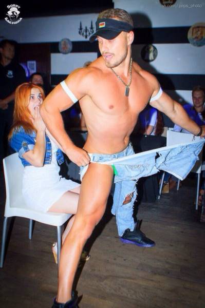 A Manhattan male stripper dressed as a firefighter performing at a party with cheering guests