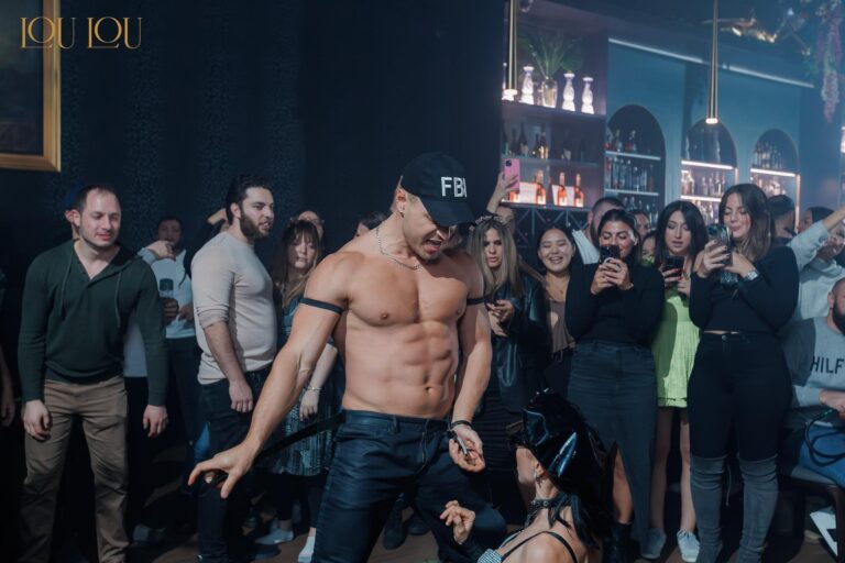 Professional male stripper performing at a bachelorette party in NYC, with guests cheering and enjoying the show